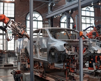 gray vehicle being fixed inside factory using robot machines